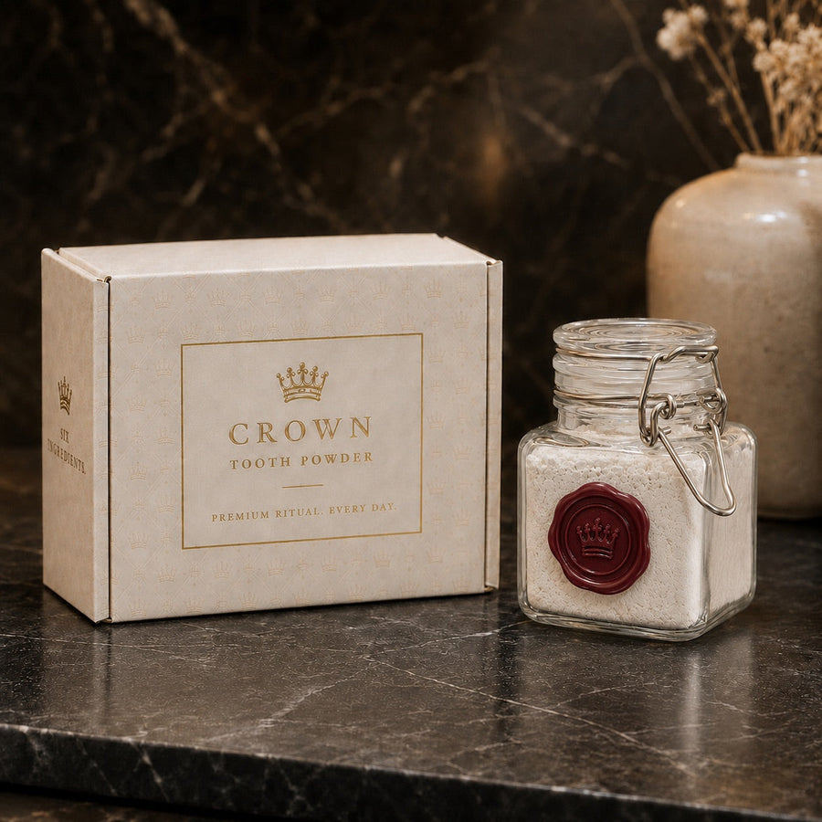 A Crown Tooth Powder box and a sealed glass jar of white powder photographed on dark marble
