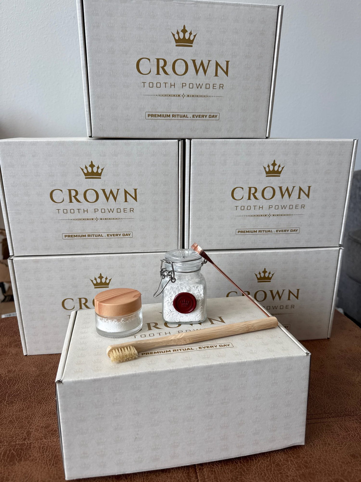Stack of printed Crown Tooth Powder boxes with the kit components arranged in front.